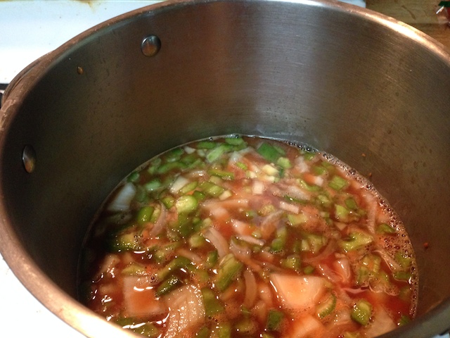 Pot with vegetables and a somewhat red stock.